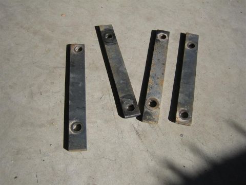 1987 Suzuki Samurai - Four metal brackets with holes are laid out on a concrete surface.