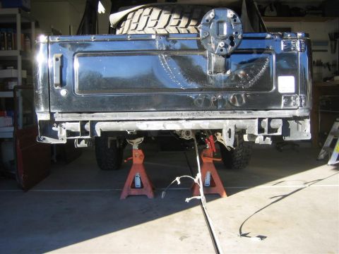 1987 Suzuki Samurai - The rear of a black 1987 Suzuki Samurai is elevated on jack stands inside a garage.
