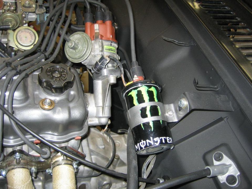 engine bay with distributor and ignition coil wrapped in Monster Energy logo tape