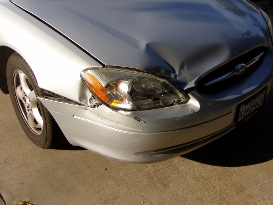 Front-end collision damage on a silver Ford Taurus