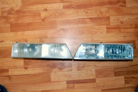 1985 Mercury Grand Marquis - Pair of car headlights displayed on a wood-planked surface.