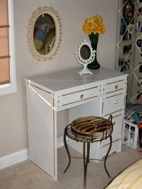 1985 Ford Crown Victoria LTD - A vanity desk setup includes a stool, decorative mirror, and a vase of yellow flowers.