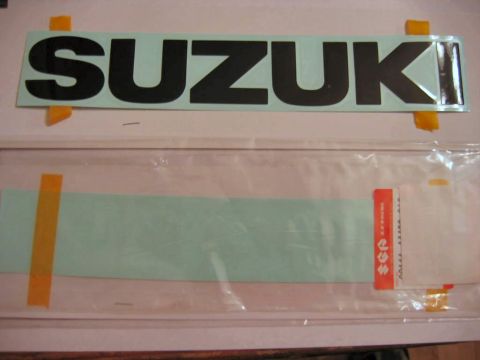 1985 Ford LTD Crown Victoria - A large black 'SUZUKI' decal is shown, with a second decal in packaging below it, still in its packaging.