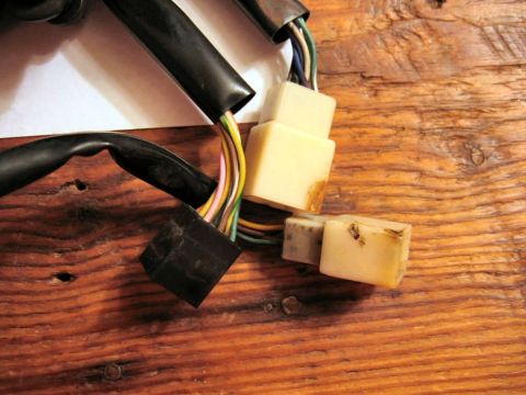 1985 Ford LTD Crown Victoria - Close-up of electrical connectors and wires, likely from a vehicle or machine, resting on a rustic wooden background.
