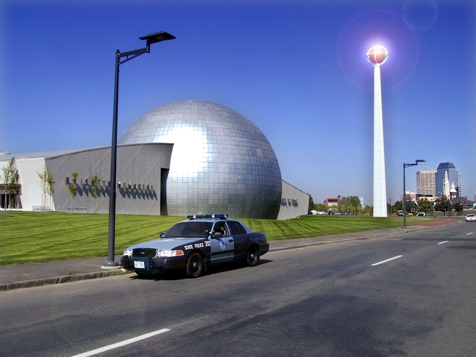Blue and gray State Police Crown Victoria parked in front of the Basketball Hall of Fame's silver dome