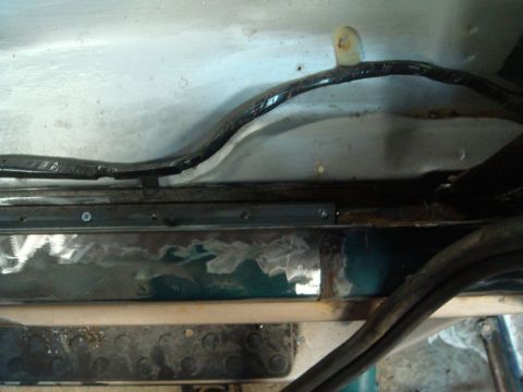 1996 Ford Bronco - Repair work on the bottom door jam area of a vehicle, with visible wiring and metalwork.