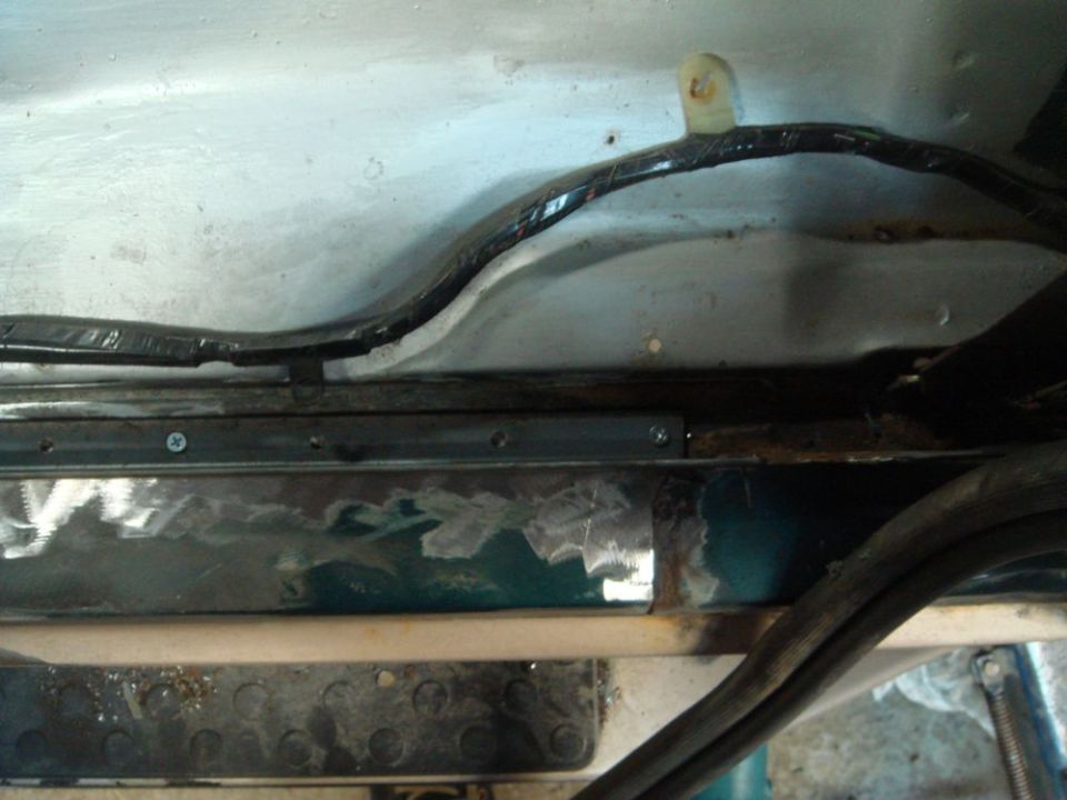 Close-up of vehicle underbody showing metal repair and wiring harness