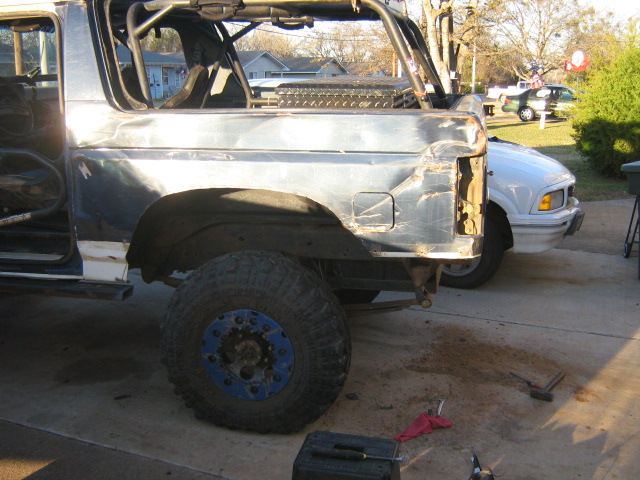 Roofless Ford Bronco project with roll cage and trimmed rear quarter panel in a driveway