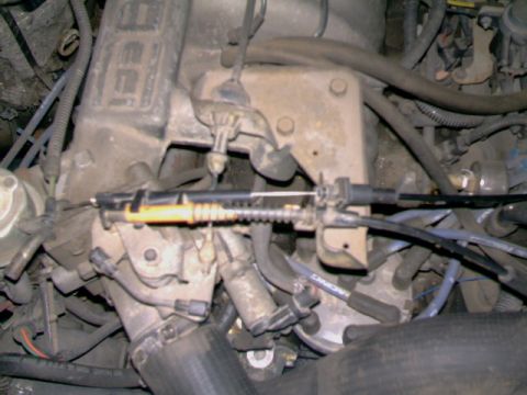 1989 Ford Bronco - Detail of the throttle cable assembly and surrounding engine components in a vehicle.