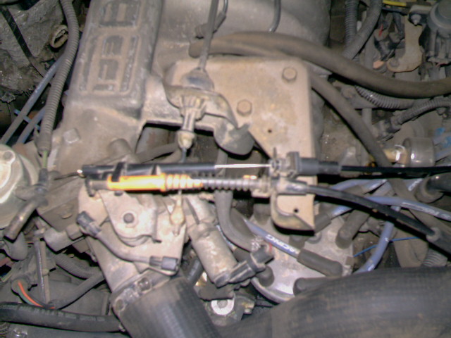 Close-up of engine bay showing throttle cable mechanism and various hoses and wires