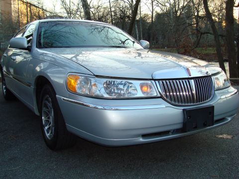 2002 Lincoln Town Car - Front view of a silver 2002 Lincoln Town Car parked on asphalt with trees and water in the background.