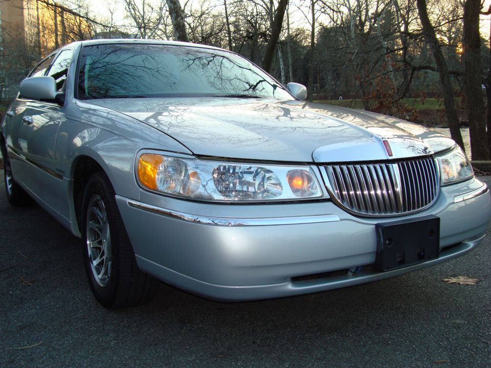 Silver 2002 Lincoln Town Car front view, parked outdoors with trees in background