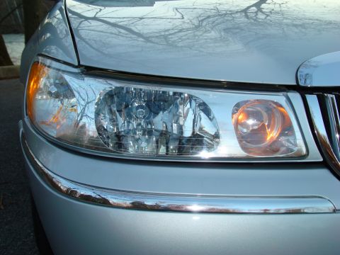 2002 Lincoln Town Car - Close-up of the front passenger side headlight and grille of a silver Lincoln Town Car.