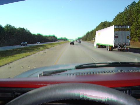 1986 Ford Bronco - Driving on the highway behind a J.B. Hunt semi-truck, with other vehicles visible.