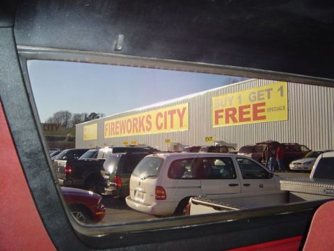 1986 Ford Bronco - A view of a parking lot outside a Fireworks City store, with several vehicles visible.