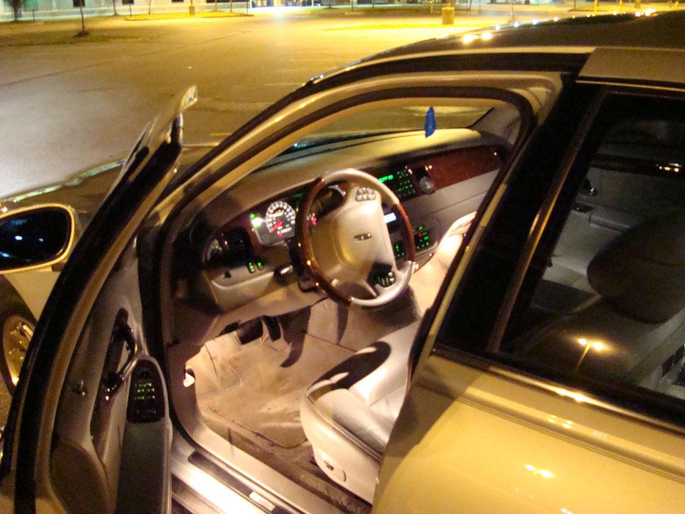 car interior with wood trim on steering wheel and dashboard, illuminated gauges
