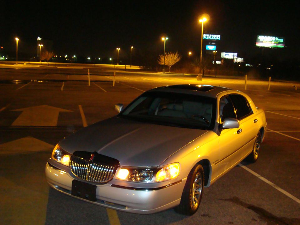 Silver 2002 Lincoln Town Car parked at night, front 3/4 view, illuminated by streetlights