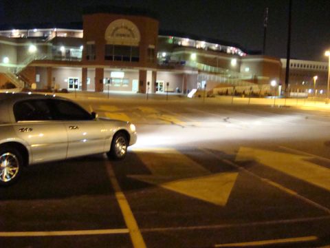 2002 Lincoln Town Car - A silver sedan is parked in a lot at night, with its headlights illuminating the ground.