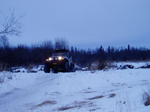 2000 Ford E350 - Jeep Wrangler navigates a snowy landscape under a cloudy sky.