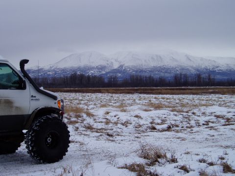 2000 Ford E350 - Modified 2000 Ford E350 van equipped with a snorkel and large off-road tires sits in a snow-covered field with mountains in the background.