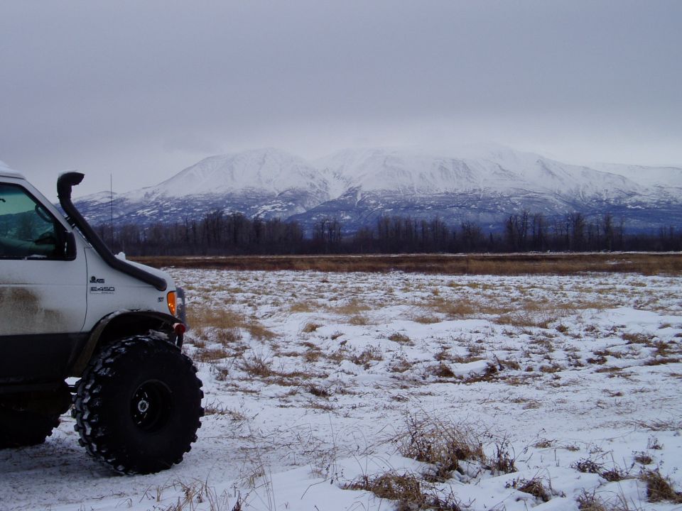 White 2000 Ford E350 with snorkel and oversized tires in snowy landscape