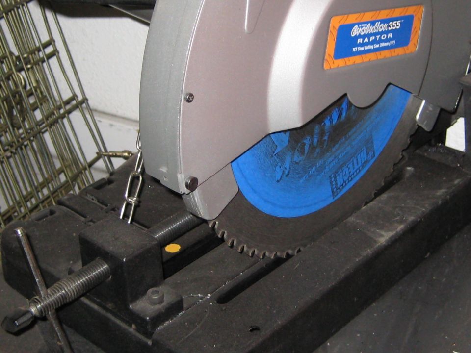 Evolution 355 Raptor metal cutting saw with blue blade and chain attached to vise