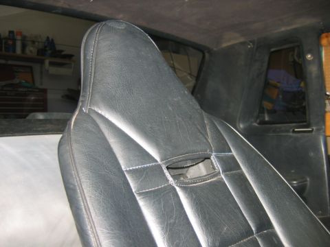 1992 Ford Mustang - The interior of a vehicle shows a close-up of a black seat with visible stitching and a small cutout.