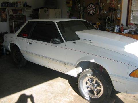 1992 Ford Mustang - A white coupe with a large hood scoop and red pinstripes is parked in a garage.