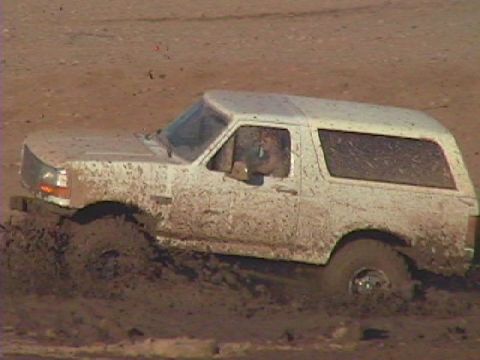 1992 Ford Bronco - This white Ford Bronco is deep in the mud, with its tires partially submerged.
