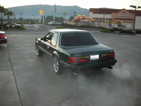 1992 Ford Crown Victoria - Green 1987 Ford Mustang with smoke from exhaust pipe at a McDonald's.