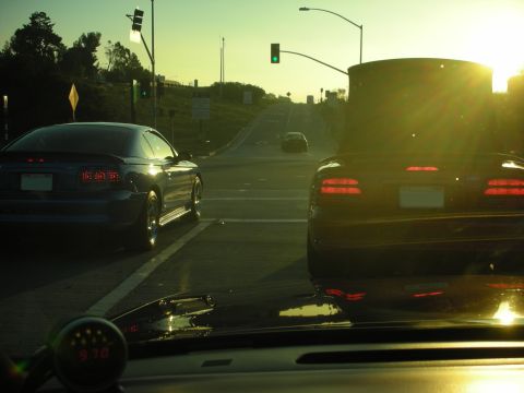1992 Ford Crown Victoria - Two cars are stopped at a traffic light during sunset, with a third car in the distance.