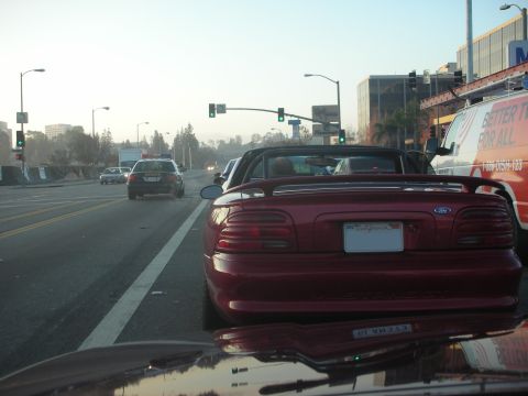 1992 Ford Crown Victoria - A red convertible is seen from behind in traffic, with a California license plate.