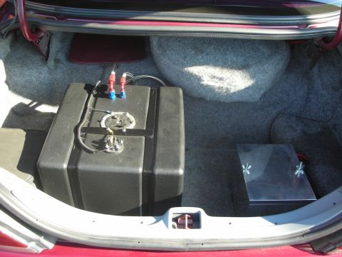 1992 Ford Crown Victoria - The trunk of a car shows an aftermarket fuel cell and a metal box, likely for performance modifications.