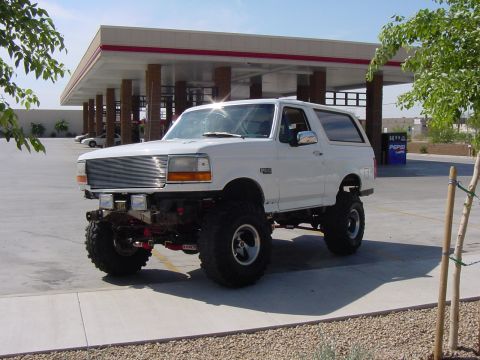 1992 Ford Bronco - White 1992 Ford Bronco with aftermarket modifications sits outside a convenience store.