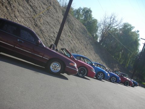 1992 Ford Crown Victoria - A row of sedans are parked on a paved surface next to a dirt hill.