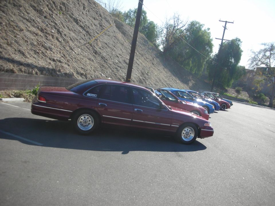 Maroon 1992 Ford Crown Victoria sedan parked in a line, side view, with aftermarket wheels