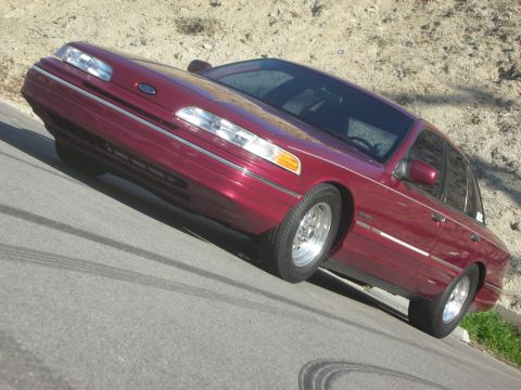 1992 Ford Crown Victoria - Maroon 1992 Ford Crown Victoria seen from the front quarter angle on a paved surface.