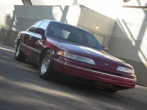 1992 Ford Crown Victoria - A maroon 1992 Ford Crown Victoria is shown from a three-quarter front angle.