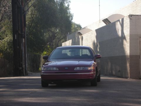 1992 Ford Crown Victoria - A maroon 1992 Ford Crown Victoria is parked on a street in front of a brick building.
