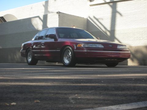 1992 Ford Crown Victoria - A maroon 1992 Ford Crown Victoria is shown from a 3/4 front angle in front of a brick wall.