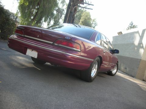 1992 Ford Crown Victoria - Maroon 1992 Ford Crown Victoria sedan parked on asphalt, viewed from the rear quarter angle.