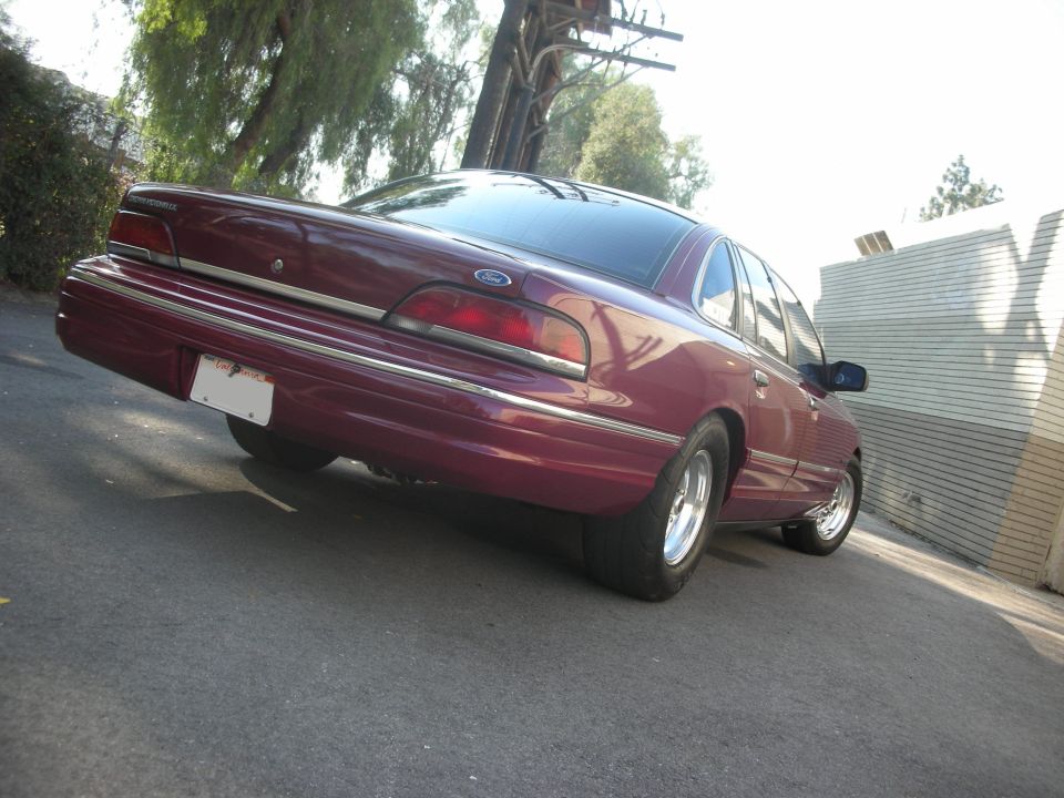 Maroon 1992 Ford Crown Victoria sedan, rear 3/4 view, with chrome wheels and aftermarket rear tires