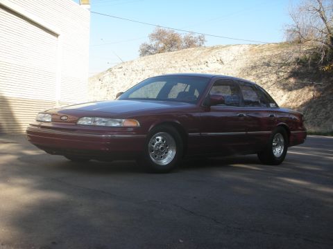 1992 Ford Crown Victoria - Maroon 1992 Ford Crown Victoria parked on asphalt with a hillside in the background.