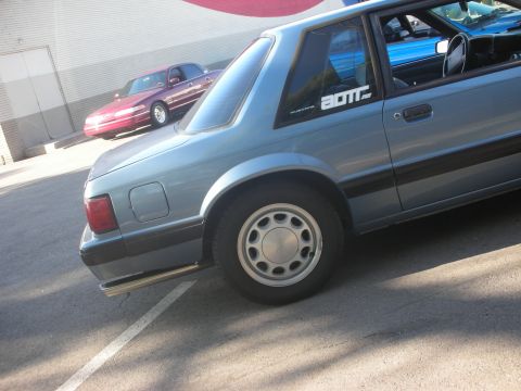 1992 Ford Crown Victoria - Two cars are parked in a lot, one light blue and one red.