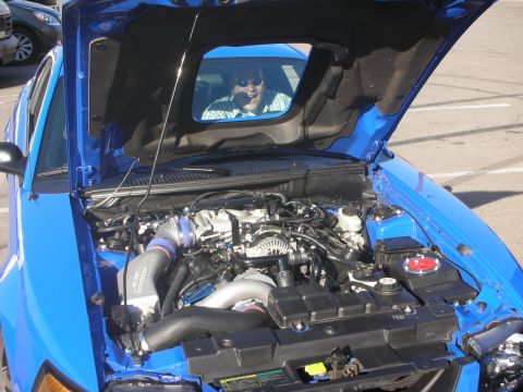 1992 Ford Crown Victoria - The engine bay of a bright blue car is open for viewing, with a person visible through the windshield.