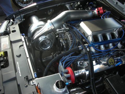 1998 Ford Crown Victoria - Customized engine bay a large turbocharger, polished components, and vibrant blue wiring, suggesting performance modifications.
