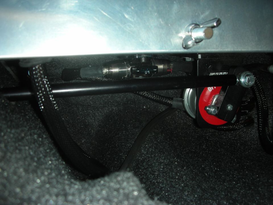 Underside detail of an aluminum panel with a battery cutoff and wiring