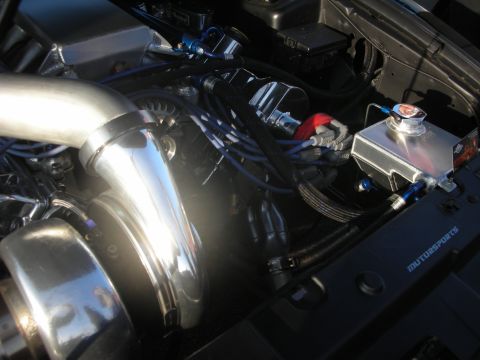1998 Ford Crown Victoria - Engine bay details with custom chrome turbocharger and aluminum coolant reservoir, showing 'MUTURSPORTS' text.