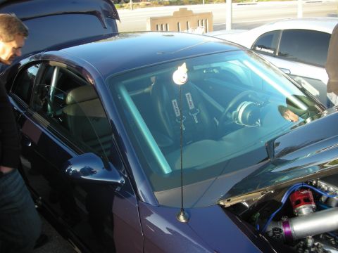 1998 Ford Crown Victoria - A customized dark blue sedan is shown with racing seats, a roll cage, and engine components, parked next to another vehicle.
