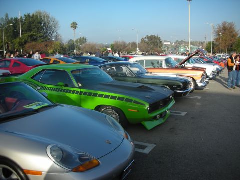 1998 Ford Crown Victoria - A row of classic cars are parked in a lot under a clear blue sky.